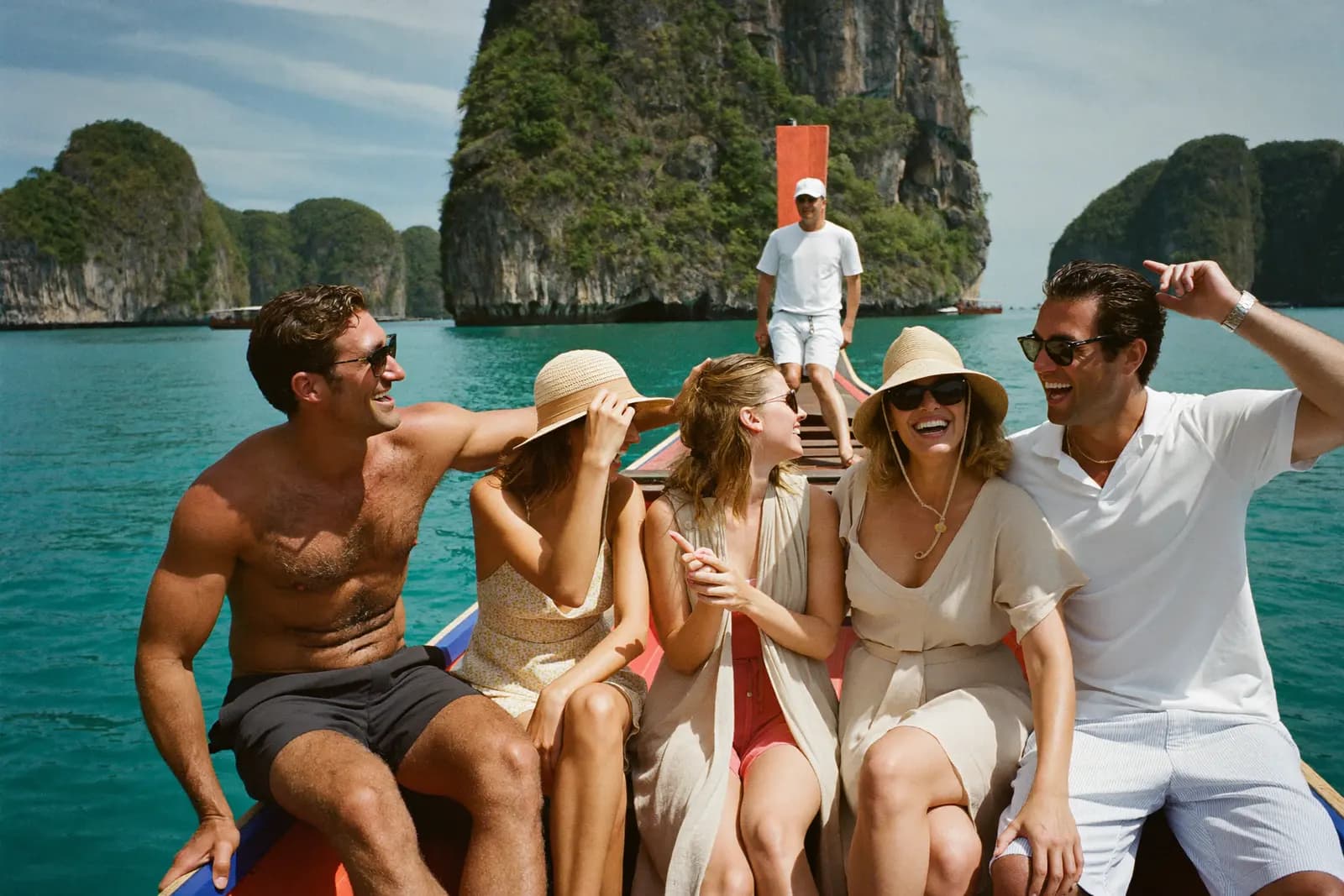 Gruppe lacht auf einem Longtail-Boot in türkisem Wasser vor Phuket