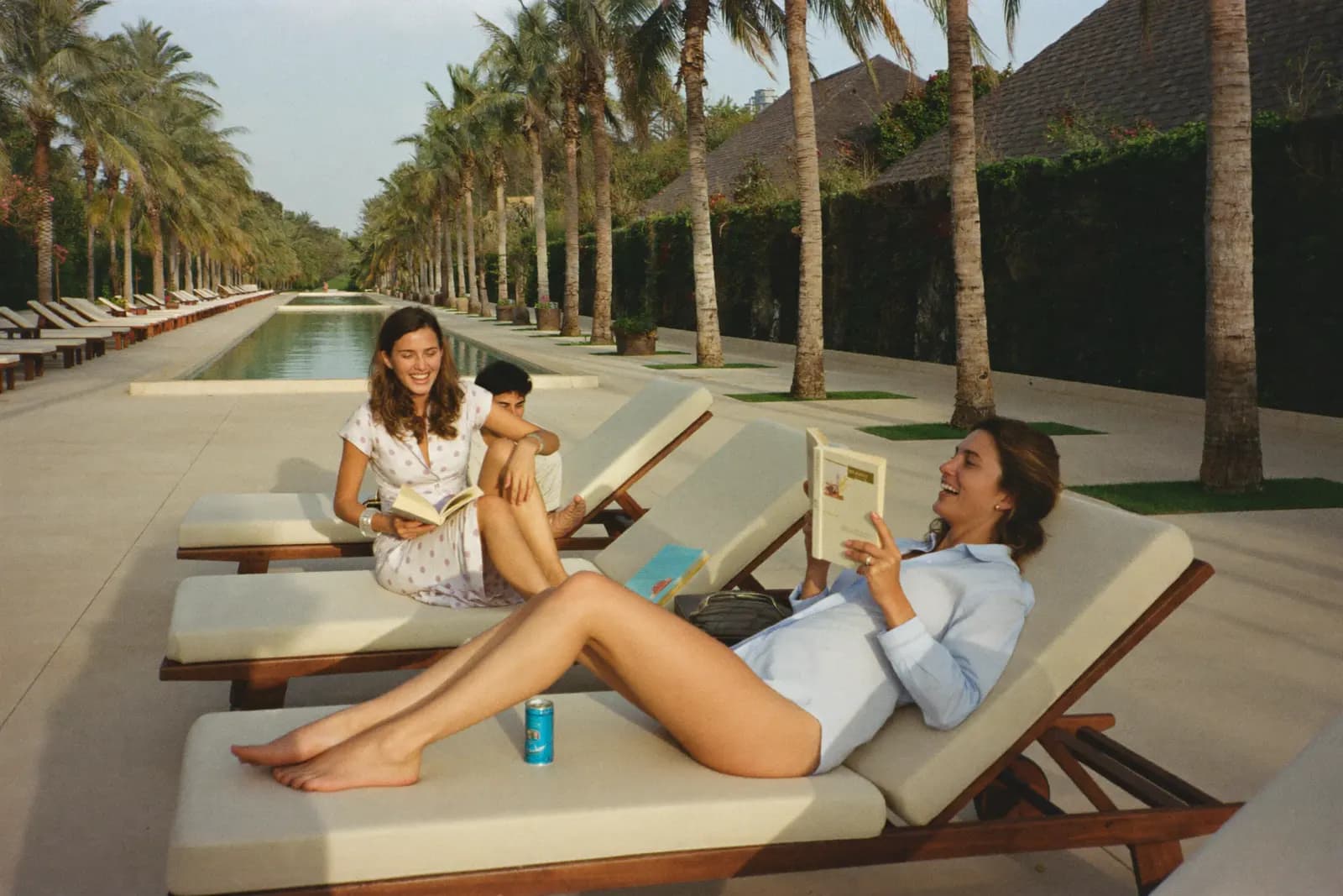 Gäste entspannen lachend mit Büchern auf Liegen am Resort-Pool